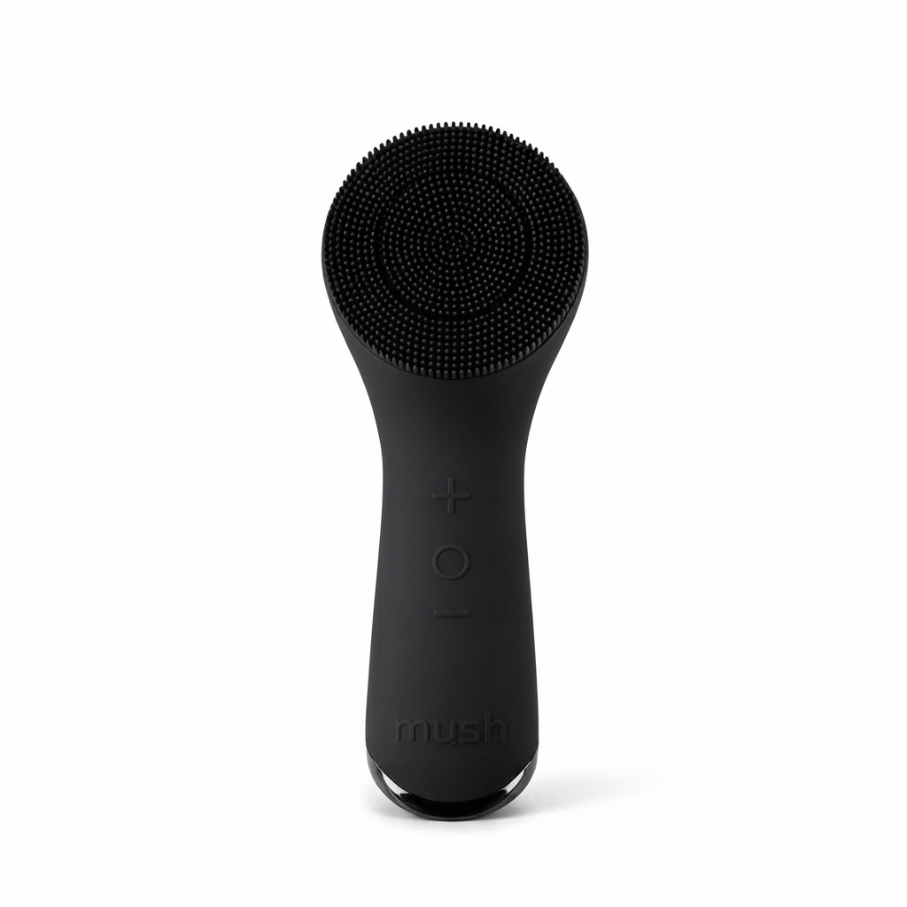 A matte black Mush facial cleansing brush with a flexible silicone bristle head, shown upright against a solid white background.