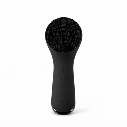 A matte black Mush facial cleansing brush with a flexible silicone bristle head, shown upright against a solid white background.