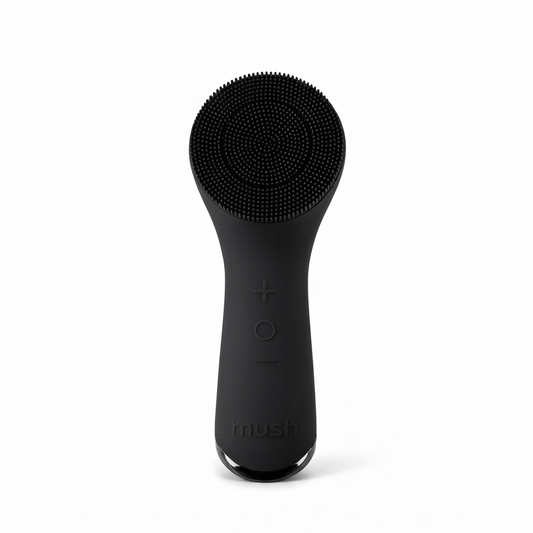 A matte black Mush facial cleansing brush with a flexible silicone bristle head, shown upright against a solid white background.